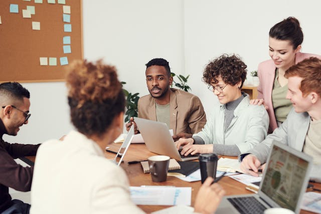 A group of people around a table with laptops and documents