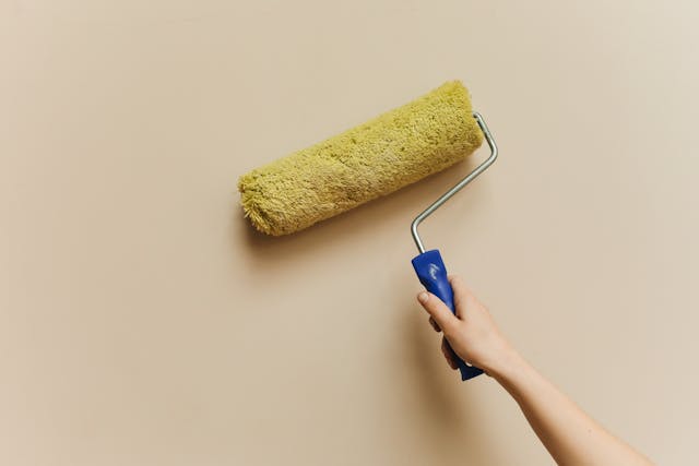 Persons hand rolling a paint roller on a wall