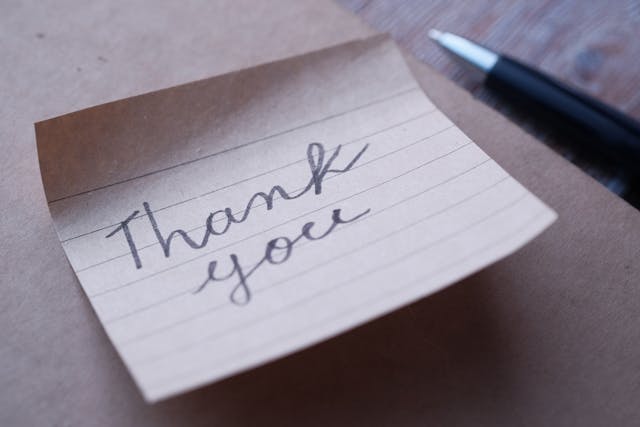 A thank you note next to a pen