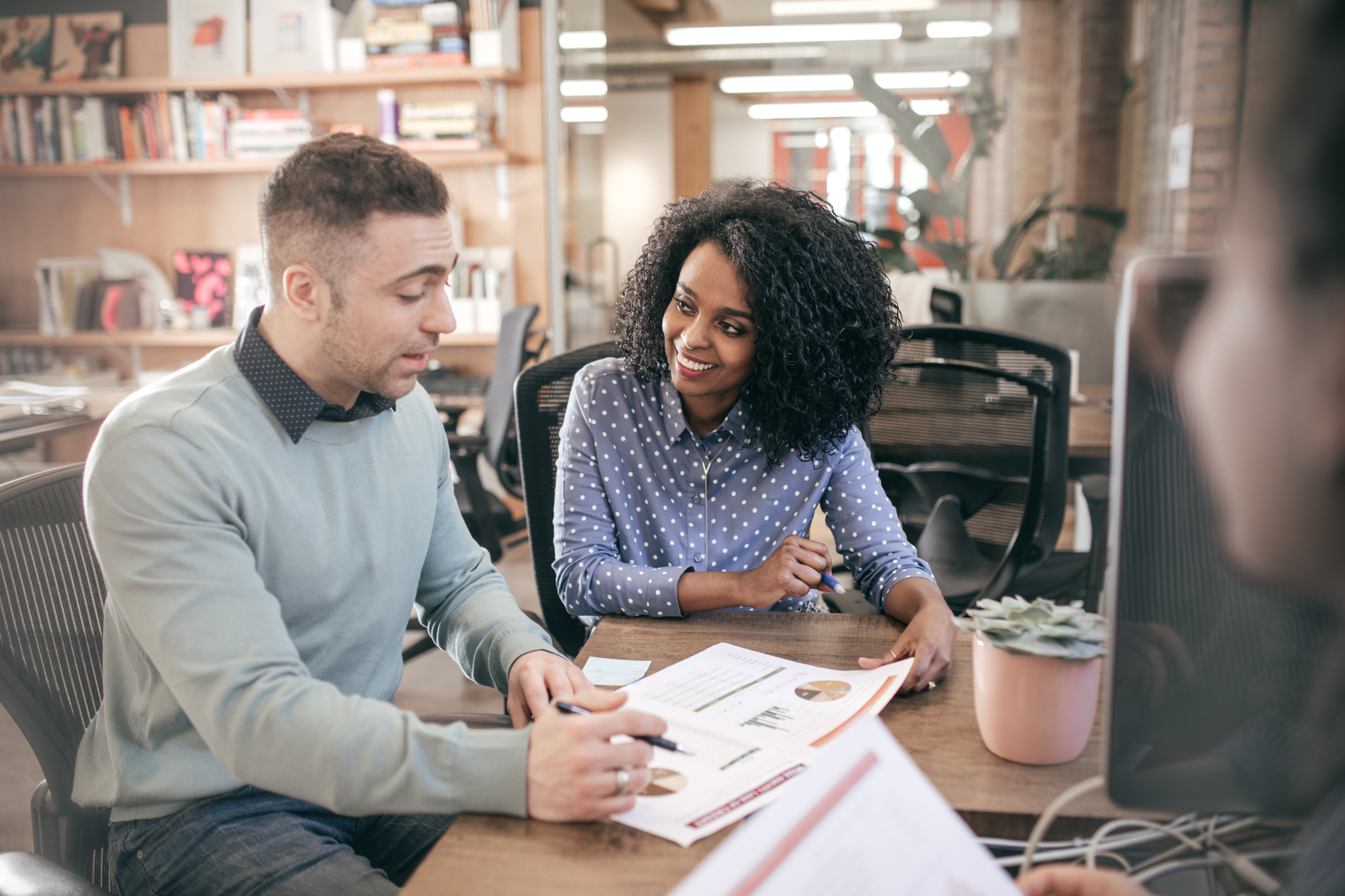 Two people sitting next to eachother at a table wile looking at graphs on a paper