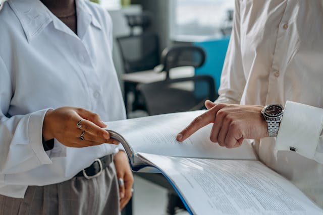 Person holding paper work while pointing at it with another person
