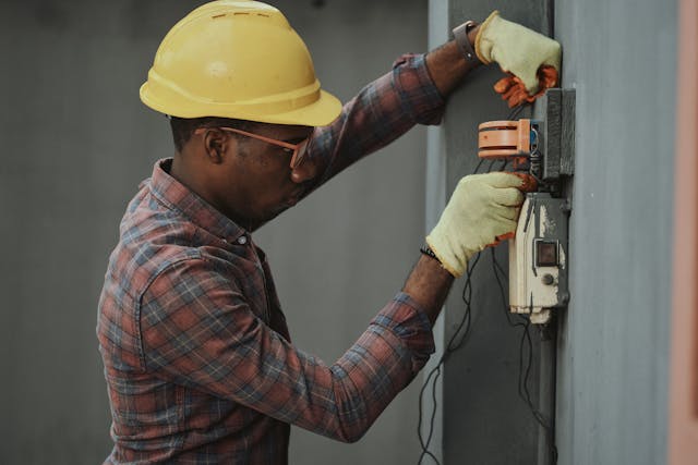 Person wearing a safety hat and gloves fixing wiring