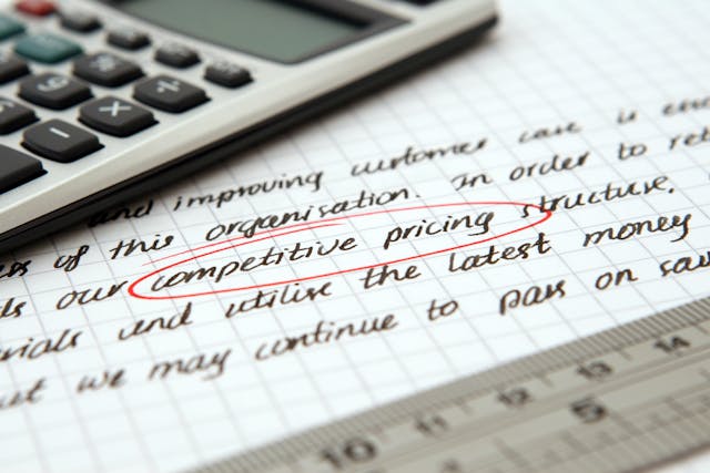 A calculator on a piece of paper displaying the words “competitive pricing” circled in red