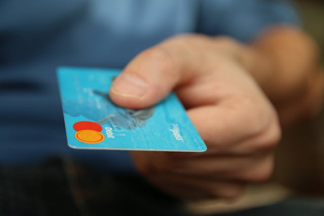 A close-up of a person's hand holding a debit card
