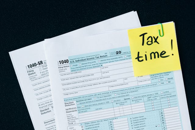 Documents paper clipped together with a yellow note that reads “Tax time!”